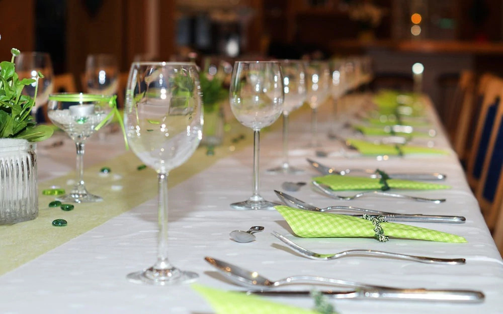 Table blanche décorée de serviettes jaunes et d'un chemin de table, y sont disposés des verres et des couverts.