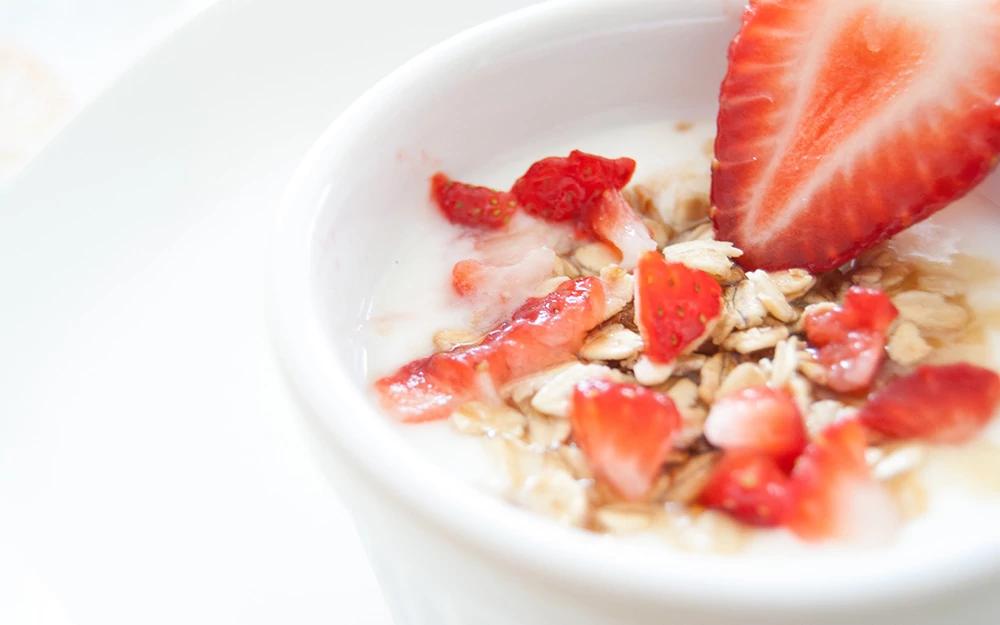 Fraise coupée en deux dans du fromage blanc et flocons d'avoine.